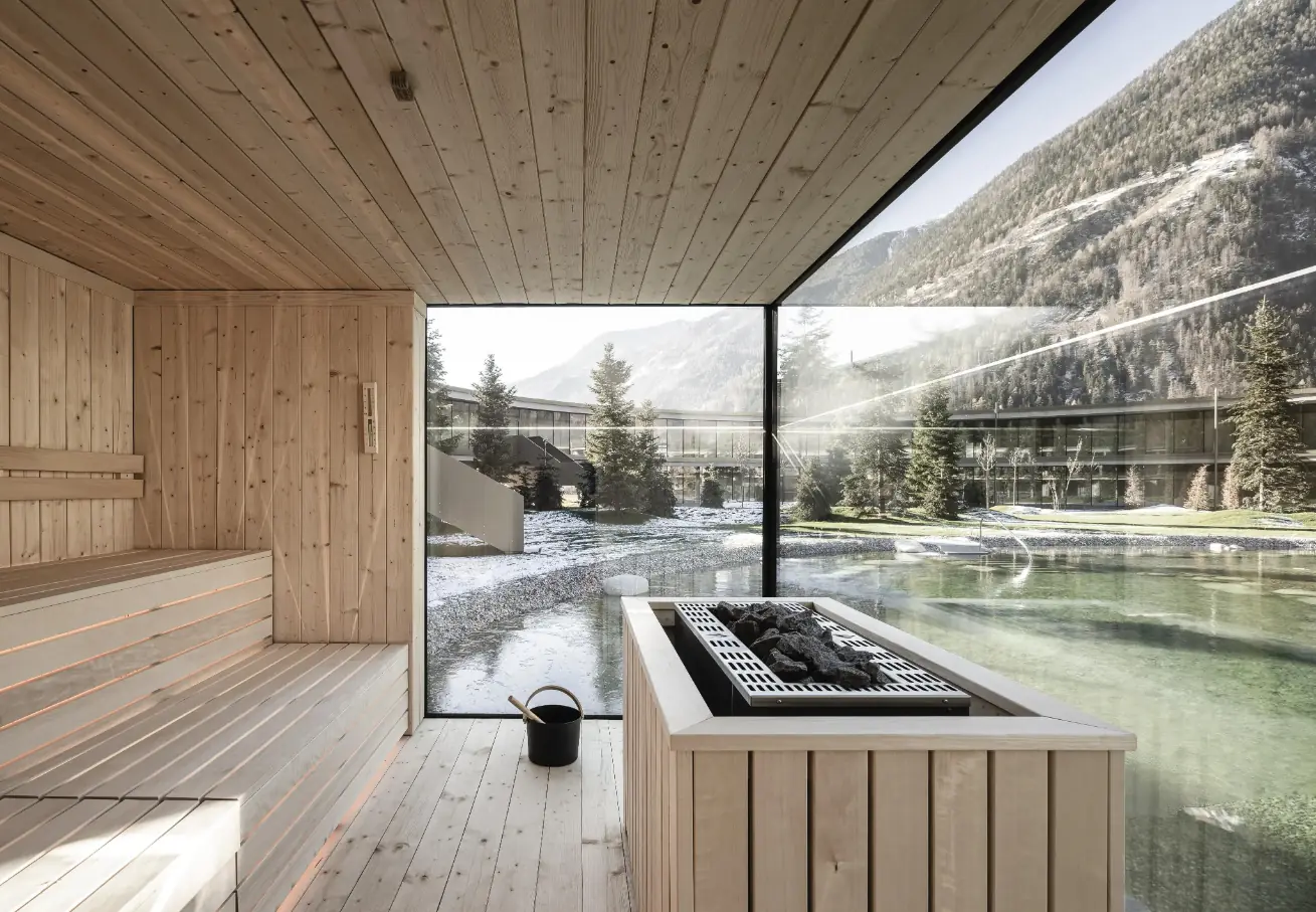 Sauna mit Panoramaverglasung und Blick auf Naturpool und Berge